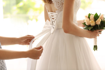 Bridesmaid tying bow on wedding dress