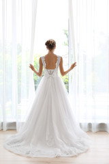 Fototapeta na wymiar Bride in a beautiful wedding dress standing near window