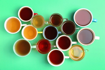 Cups of tea on green background, top view