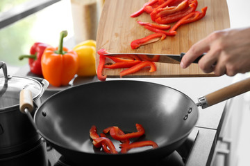 Male hands putting red pepper in pan closeup © Africa Studio