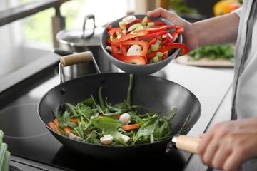 Male hands putting vegetables in pan closeup
