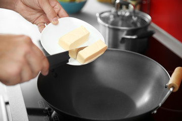 Female hand putting butter in pan closeup