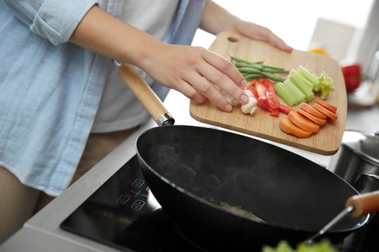 Woman hands putting vegetables in pan closeup
