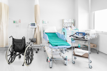 Empty wheelchair parked in hospital room with medical equipement