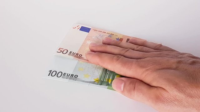 150 Euro werden von einer m&auml;nnlichen Hand auf einen Tisch geschoben