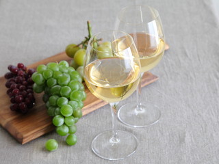 Glasses of wine with grapes on wooden board