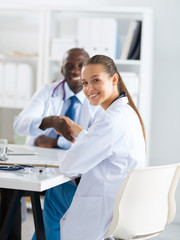 Two happy smiling young medical people handshaking at office