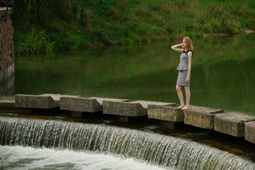 Fototapeta na wymiar Pretty young teenage girl in striped dress on river bank