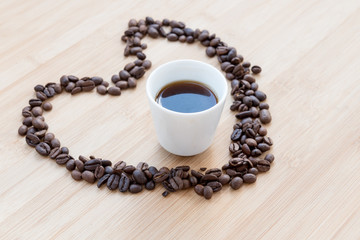 Coffee beans and black cup of coffee inside a heart