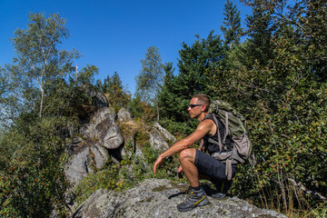 Naklejka na ściany i meble Junger Wanderer hockt auf ein Felsen, Falkenfelsen, Schwarzwald