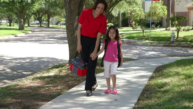 A cheerful single Hispanic mom walks with her cute little girl after school on beautiful afternoon.