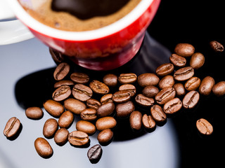Red cup of coffee with coffee beans and dark background
