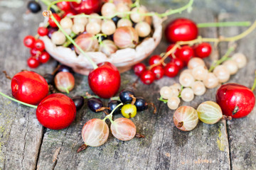 Currants, cherries and other summer fruits with old wood texture