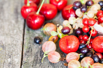 Currants, cherries and other summer fruits with old wood texture