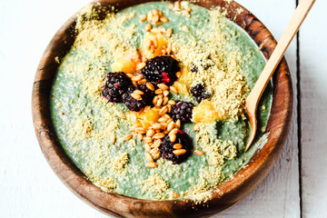 smoothies bowl with spirulina, sprouts and fruit in a wooden dis