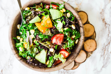 fresh green salad with avocado and corn in wooden plate,top view