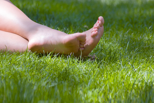 A young woman's legs on green grass.  Focus is on the feet.