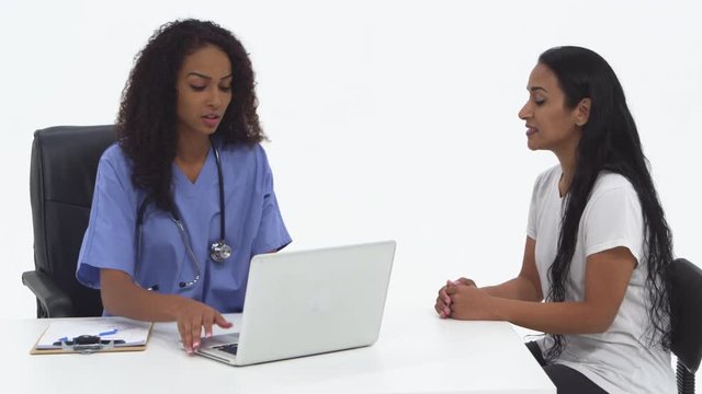 Nurse using laptop and speaking with female patient