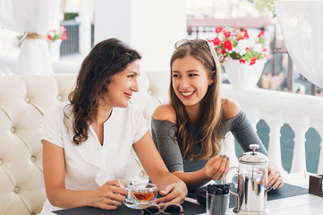 Portrait of teenage daughter and her mother having lunch together at the street cafe.