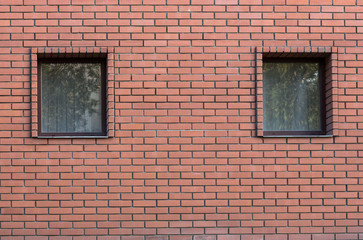two windows on a background of red brick wall