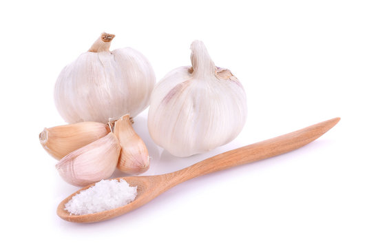 Salt on wooden spoon and garlic White background