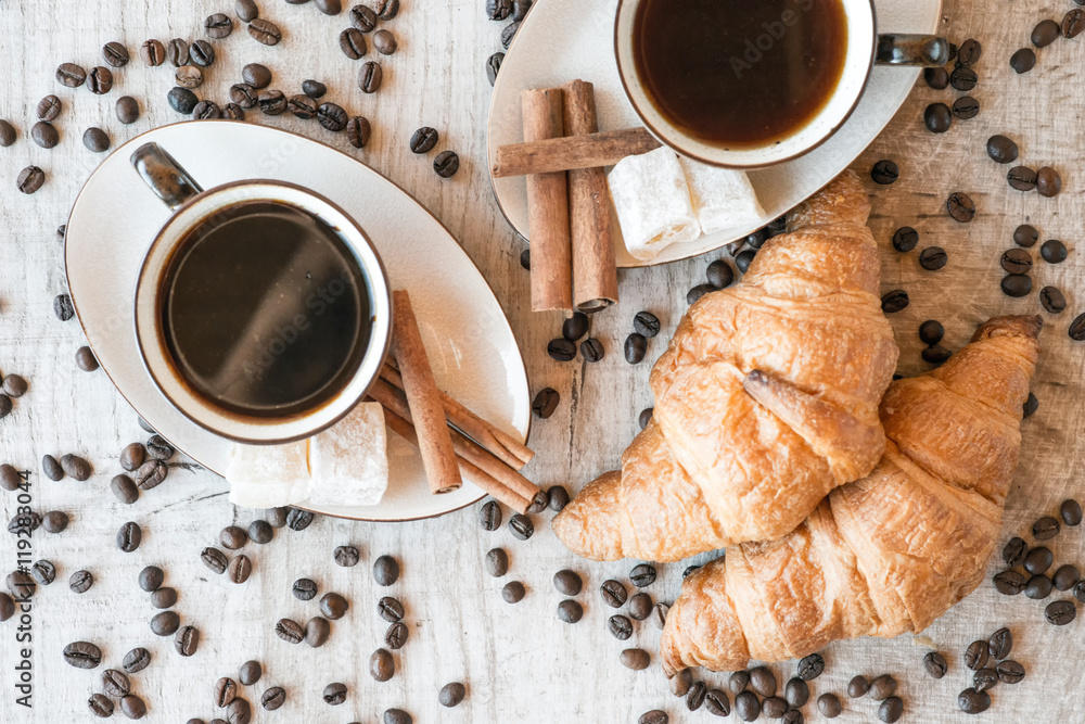 Wall mural cup of coffee with grains, croissant, turkish delight and cinnamon sticks on wooden background