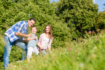 Fototapeta premium Familie kuschelt gemeinsam auf der Wiese