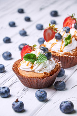 Pastries with blueberries, strawberries, whipped cream and mint. fresh berries in the background.