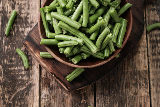 Bunch of freshly picked green beans on a wooden surface.