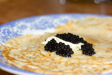 Black caviar on Russian pancakes. Selective focus.