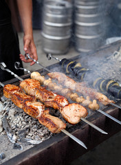 Preparation of barbecue meat shish kebab on skewers grill food. Man grilling traditional summer picnic marinated pork on coal ember brazier. Concept of lifestyle rustic street food preparation
