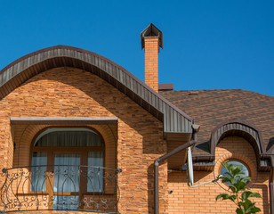 Balcony under the rounded roof with rain gutter, chimney, round windows