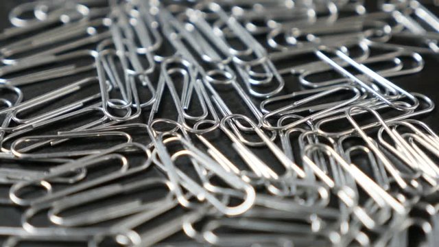 Metal or steel wire clips for documents in office on wooden table close-up slow tilt 4K 2160p 30fps UltraHD footage - Wire steel paperclips with looped shape 4K 3840X2160 UHD tilting video 