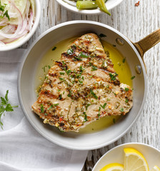 Grilled tuna steak in herb and lemon marinade served on a rustic pan