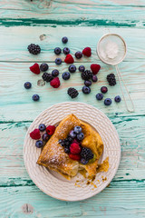 Delicious puff pastry with forest fruit on wooden table.