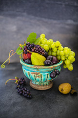 Beautiful still life with grapes and figs and other fruits on stone background.
