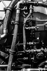 Fragment of modern technology. Details of engine pipelines. Black and white. Background.