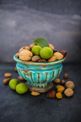 Nuts in old vase on a stone dark background. Beautiful autumn still life.
