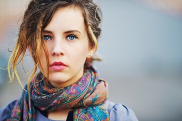 Portrait of beautiful pensive girl with messy hair in scarf with