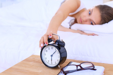 A young woman putting her alarm clock off in the morning