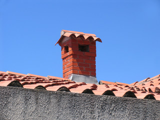 Brick chimney on the house with a tiled roof