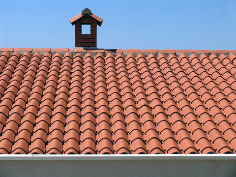 Brick chimney on the house with a tiled roof