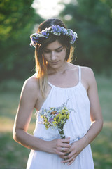 Young woman holding bouquet of wild flowers.