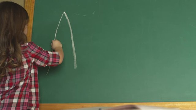 young girl writing the alphabet on chalkboard