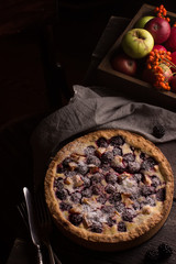 Homemade pie with apples and blackberry on wooden dark table.