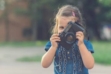 Little girl playing with old camera.