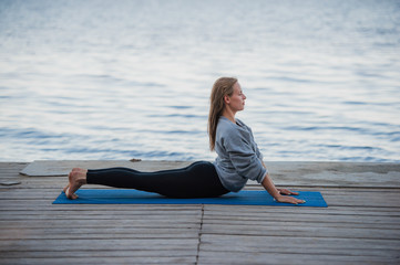 Young sport woman practicing yoga on the beach