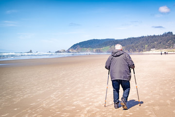 Senior man with walking sticks on the beach. Concepts: aging, exercise, fitness