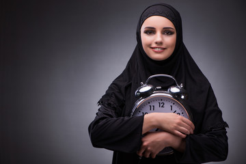 Muslim woman in black dress against dark background