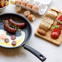 Fried sausages and eggs in a pan served with bread, tomatoes and egg shell, TOP VIEW